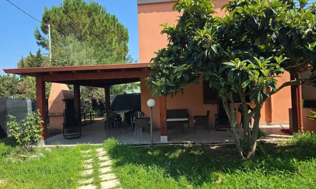 Veranda con tavolo e sedie, barbecue e alberi da frutto. Un angolo di pace tra i migliori agriturismi Sardegna sud.