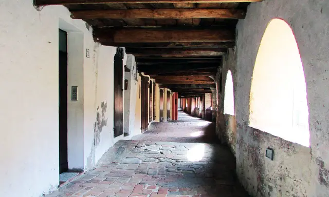 Portico con soffitto in legno e archi luminosi, pavimentazione in mattoni antichi. Un viaggio nella storia lungo la via degli asini a Brisighella.