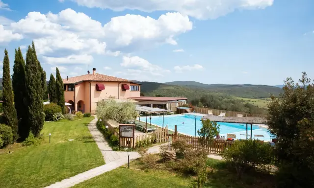 Un agriturismo in Toscana a Pasqua, con piscina azzurra e colline verdi sullo sfondo.