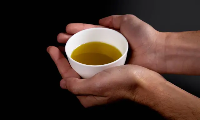 Mani che sorreggono una tazzina bianca con olio evo. Il suo significato è prezioso, un nettare dorato.