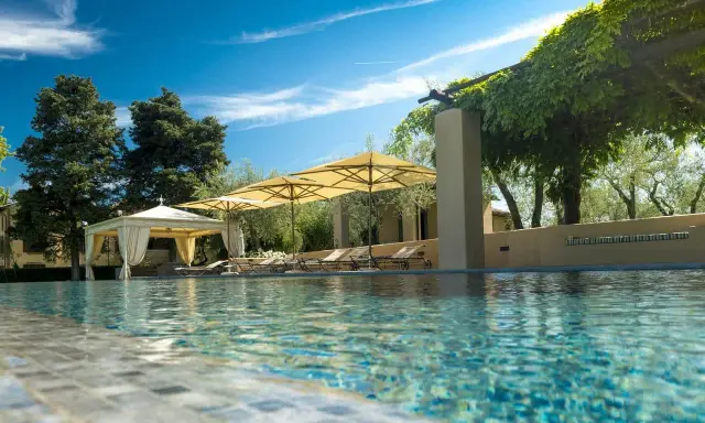Piscina con lettini e ombrelloni in un agriturismo particolare nel Lazio, immerso nel verde.