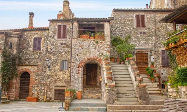 Un angolo di **Toscana, cosa vedere: borghi** antichi con case in pietra, scale fiorite e un'atmosfera senza tempo.