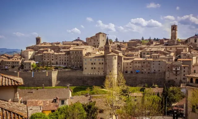 Panoramica di un borgo medievale toscano, con case in pietra e tetti in cotto, che si estende su una collina. Una dettagliata cartina borghi toscana potrebbe mostrare questo luogo.