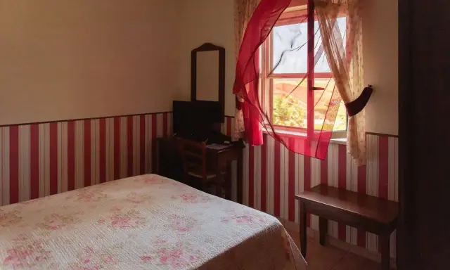 Camera accogliente in un agriturismo a Lamezia Terme, con letto fiorato e tende rosse che danzano al vento.