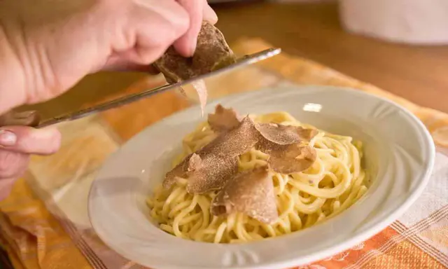 Un piatto di spaghetti conditi con tartufo fresco, un'esperienza culinaria tipica delle sagre tartufo toscana.