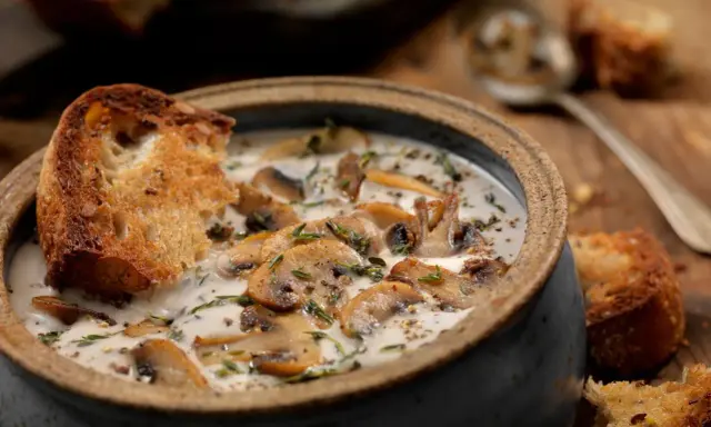 Una cremosa zuppa di funghi toscana, arricchita da erbe aromatiche e servita con crostini di pane abbrustolito.