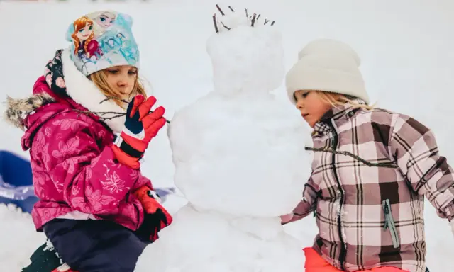 Bambini creano un pupazzo di neve in montagna, un vero natale in montagna con bambini che si divertono nella neve.