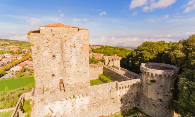 Il castello di Sarteano domina il borgo con le sue mura antiche e torri imponenti, circondato dal verde della campagna toscana.