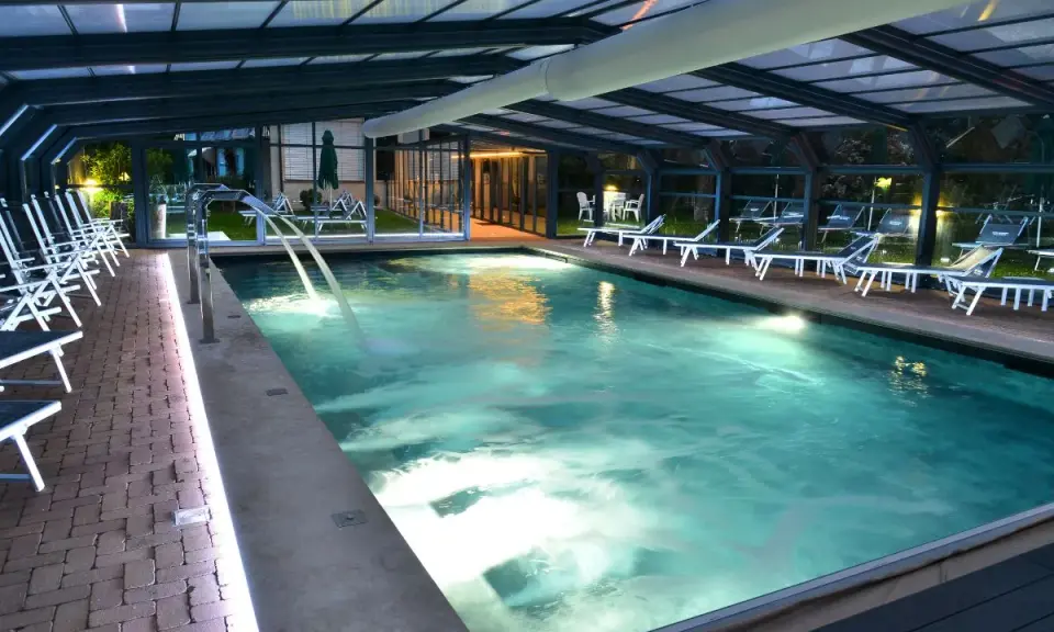Piscina coperta con lettini e cascate d'acqua, un'oasi di relax tra le migliori spa in Umbria.