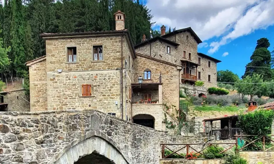 Antico ponte in pietra e case in pietra, tipici dei borghi vicino Arezzo, immersi nel verde della campagna toscana.