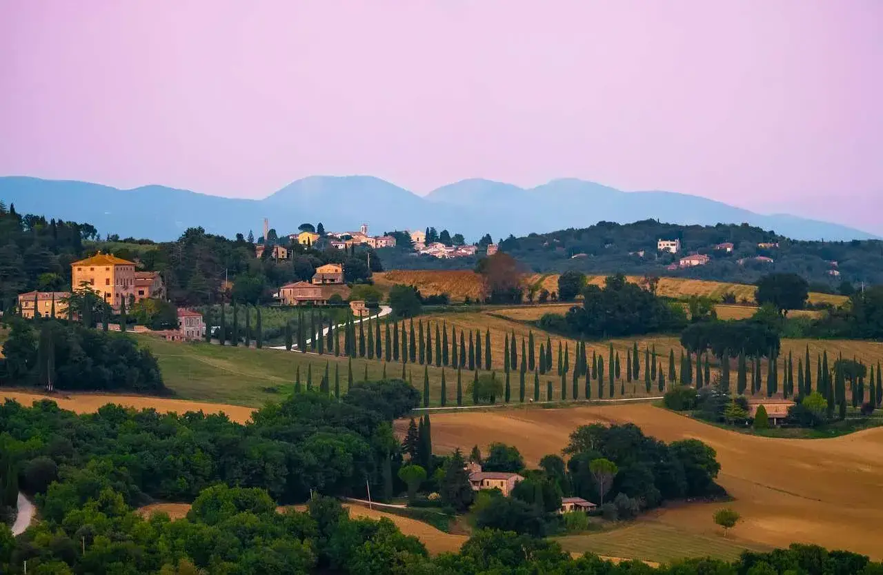 Dolci colline umbre con cipressi e casali, un paesaggio ideale per una vacanza in Umbria con bambini.