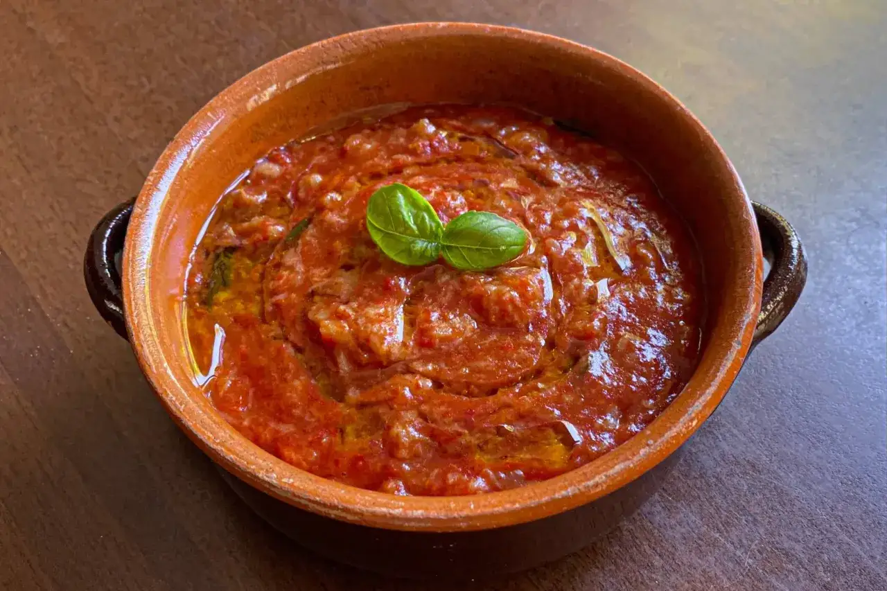 Pappa al pomodoro toscana in terracotta, guarnita con basilico fresco e un filo d'olio. Un classico della cucina povera.