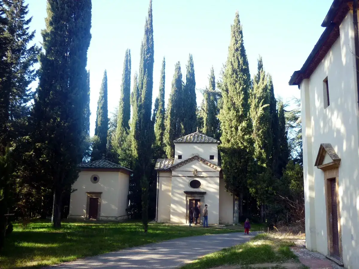 Il complesso della Gerusalemme di San Vivaldo, con cipressi svettanti e piccole cappelle, accoglie visitatori in un'atmosfera serena.