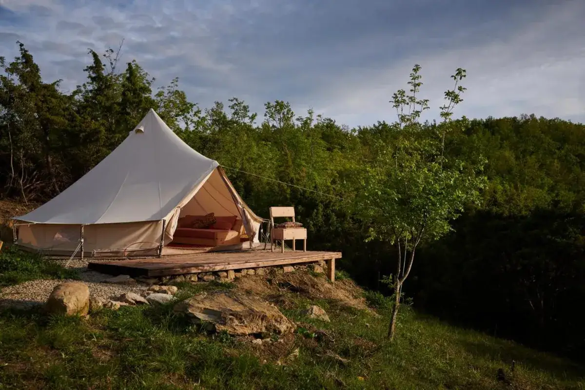 Tenda glamping su un deck in legno, immersa nel verde della natura toscana. Un invito a dormire nella natura.