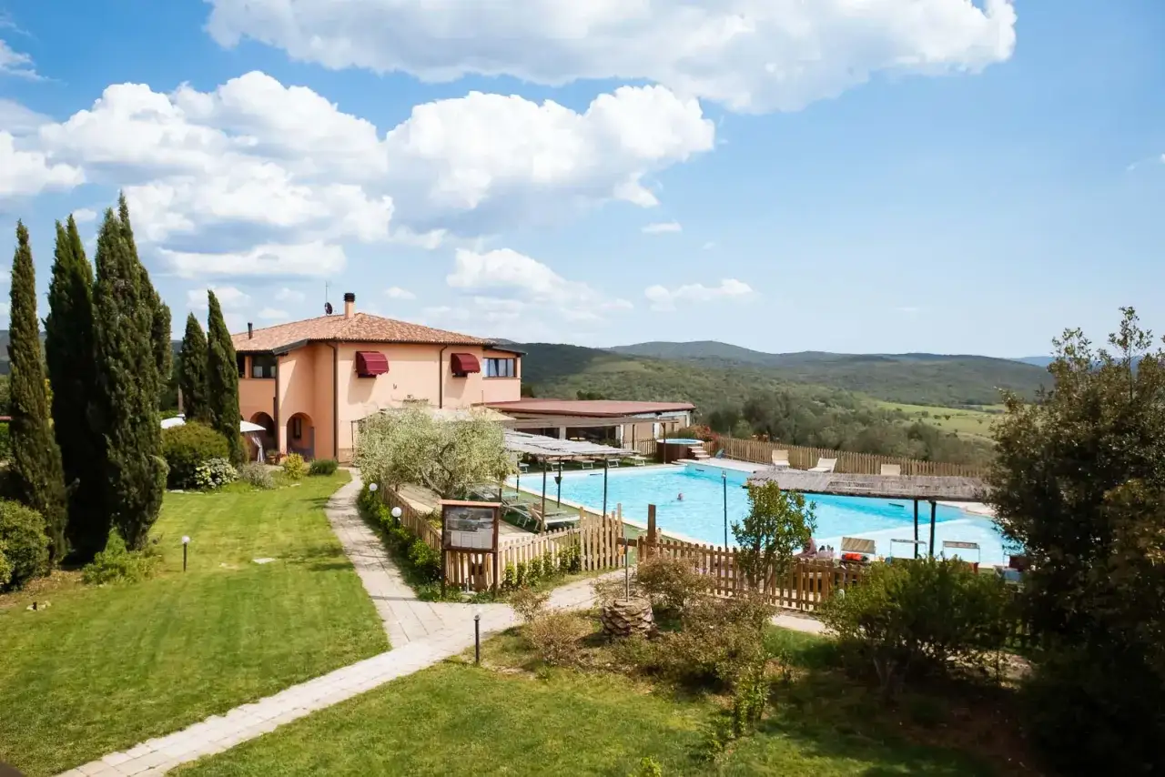 Un agriturismo in Toscana a Pasqua, con piscina azzurra e colline verdi all'orizzonte.