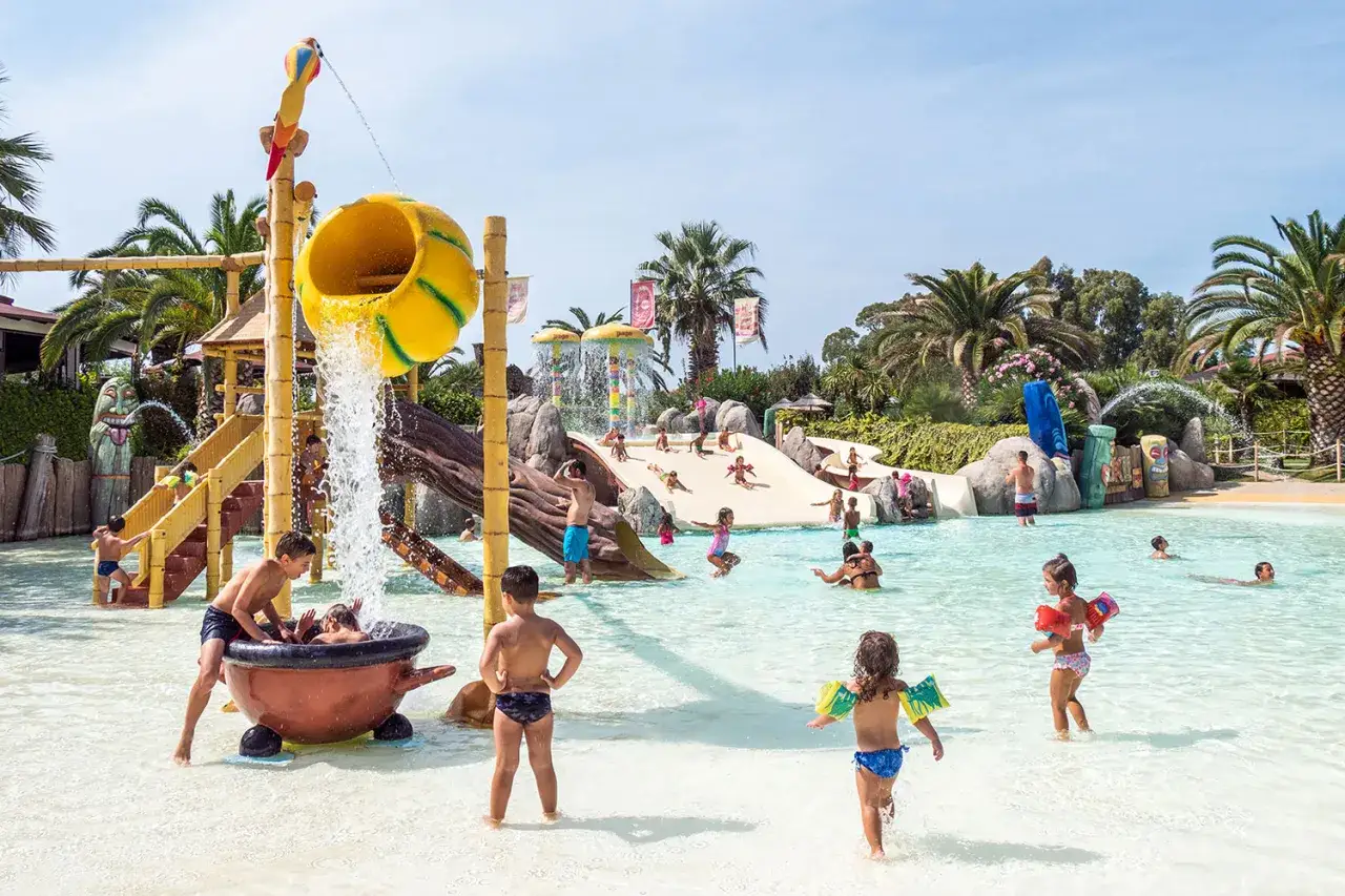 Bambini si divertono in un parco acquatico in Toscana, scivoli, cascate e giochi d'acqua per un'estate indimenticabile.