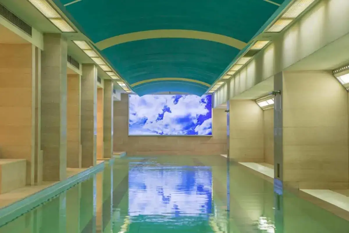 Piscina interna con soffitto a volta blu e schermo che proietta un cielo nuvoloso. Un'oasi di relax, ideale per una spa per bambini in Umbria.