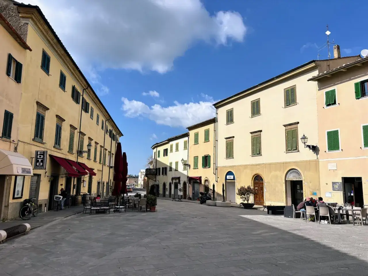 Piazza soleggiata a Pomarance, con edifici storici e tavolini all'aperto. Scopri cosa vedere in questo borgo toscano.