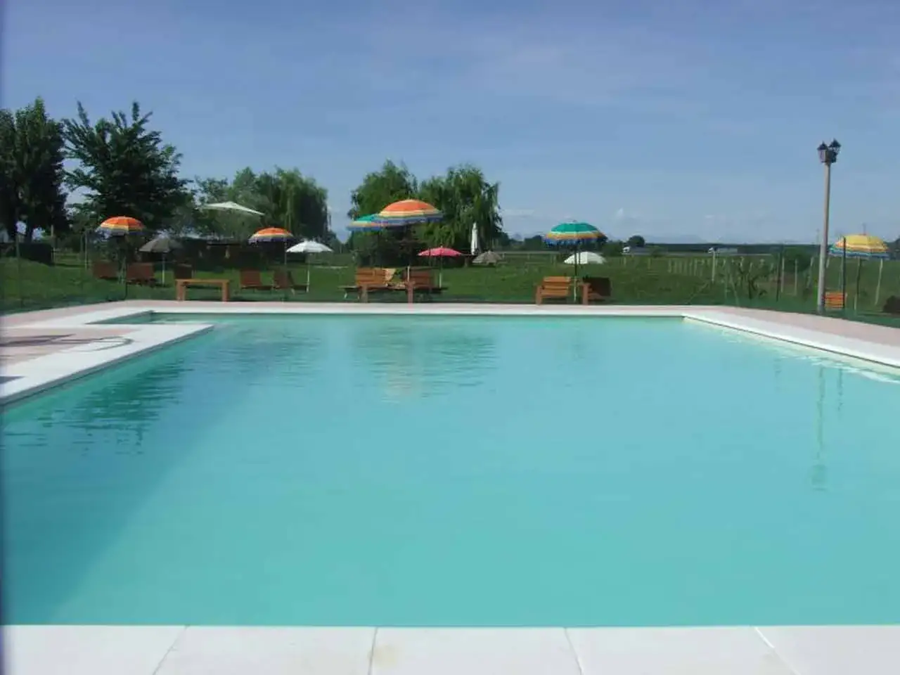 Rilassatevi in questo splendido agricampeggio con piscina, circondato dal verde e da ombrelloni colorati.