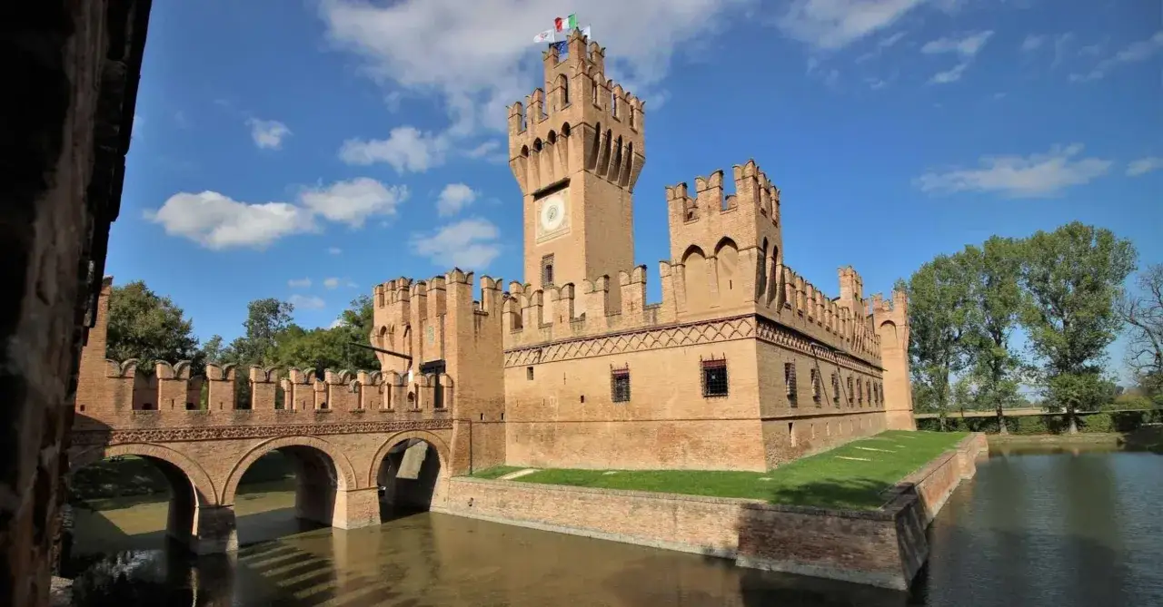 Un imponente castello in mattoni rossi, con ponte levatoio e fossato, simbolo dei castelli dell'Emilia Romagna.
