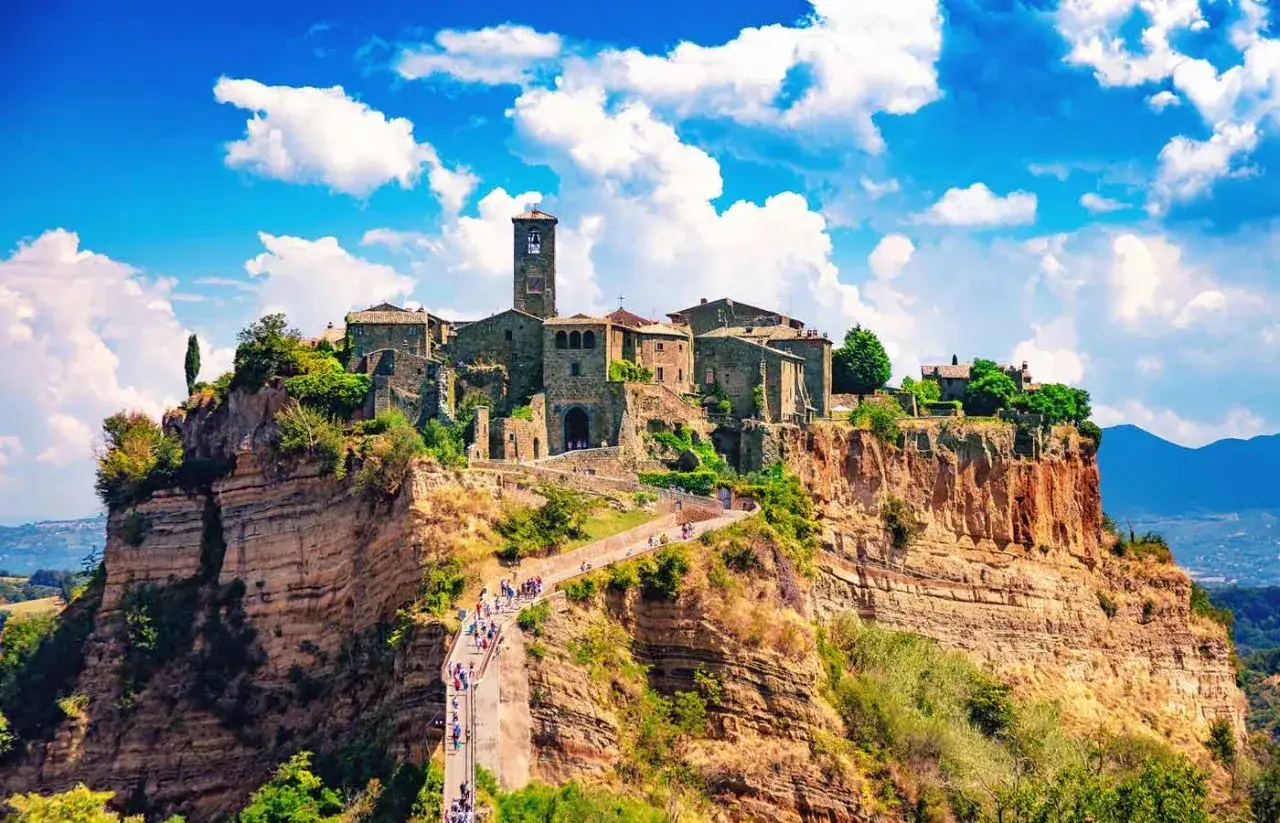 Un borgo medievale arroccato su una rupe, un gioiello della Tuscia Viterbese, con un ponte pedonale che conduce al suo centro storico.