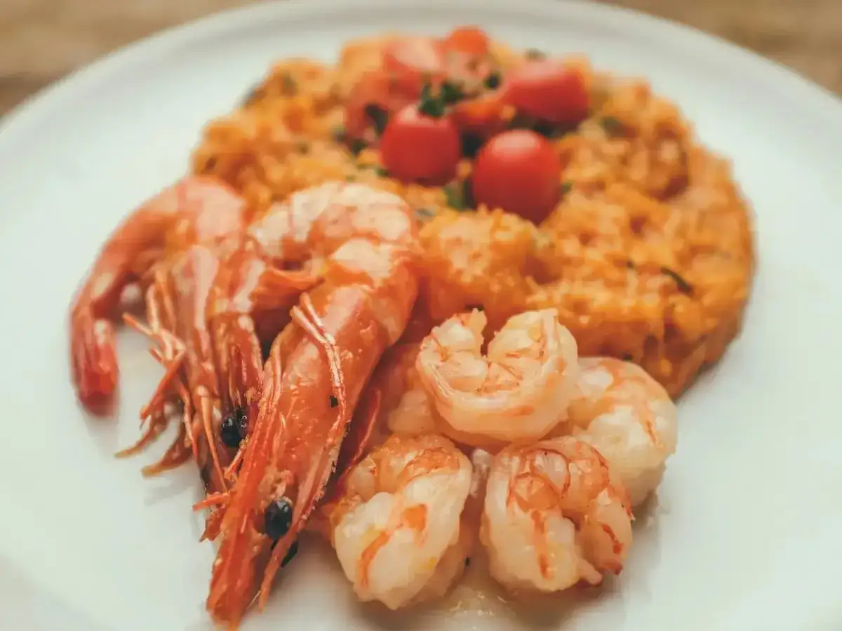 Risotto rosso con gamberi, un piatto tipico di Pavia, guarnito con pomodorini freschi.