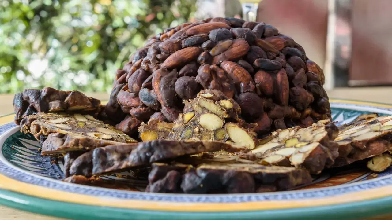 Panpepato, un dolce tradizionale con un'origine antica, ricco di frutta secca e spezie, servito su un piatto decorato.