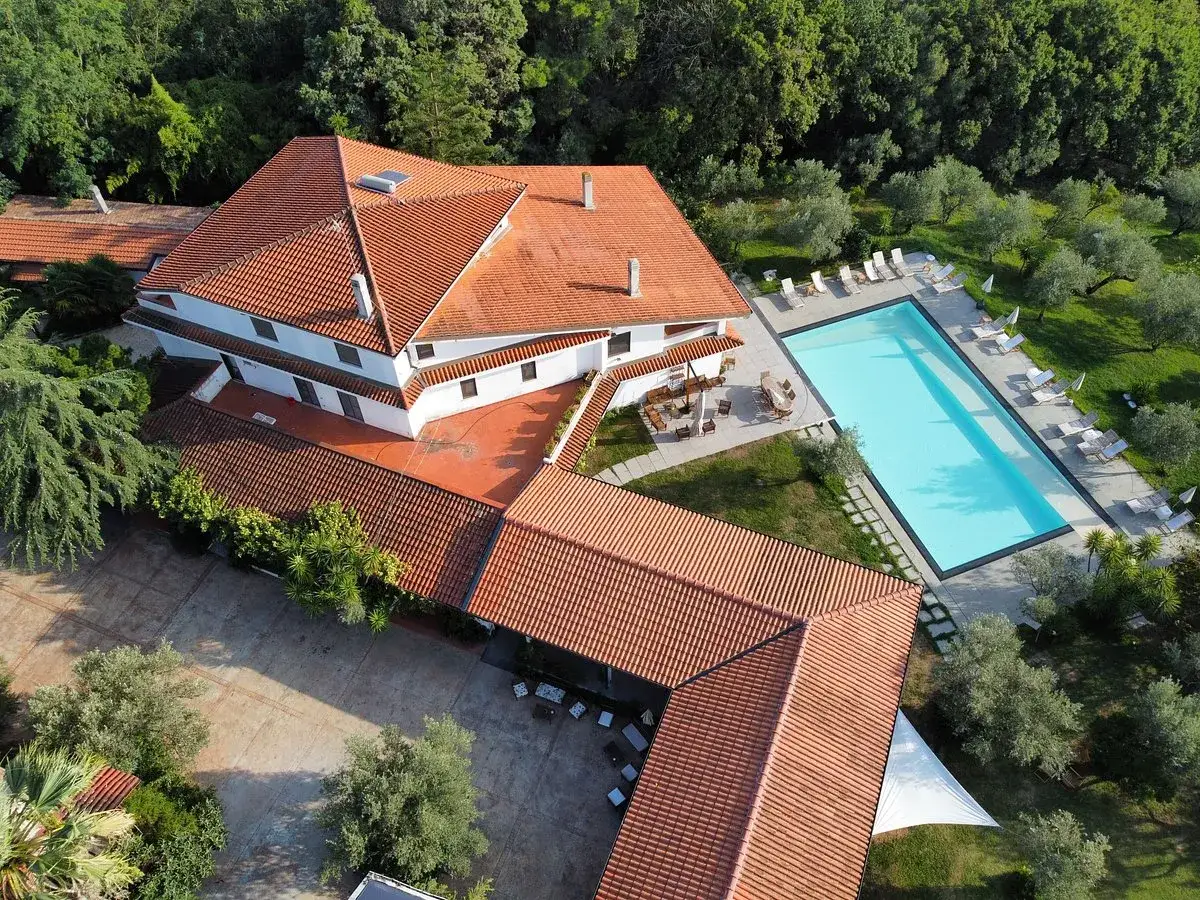 Agriturismo Lamezia Terme con piscina azzurra e lettini, circondato da ulivi e alberi. Tetti rossi e un'oasi di relax.