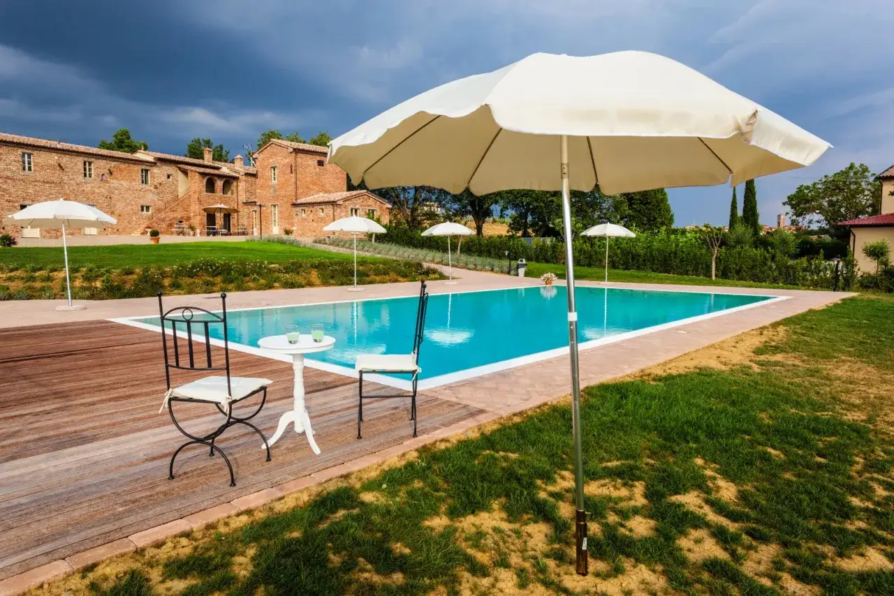Un'oasi di pace dove dormire in Toscana: piscina, ulivi e un casale in mattoni rossi.