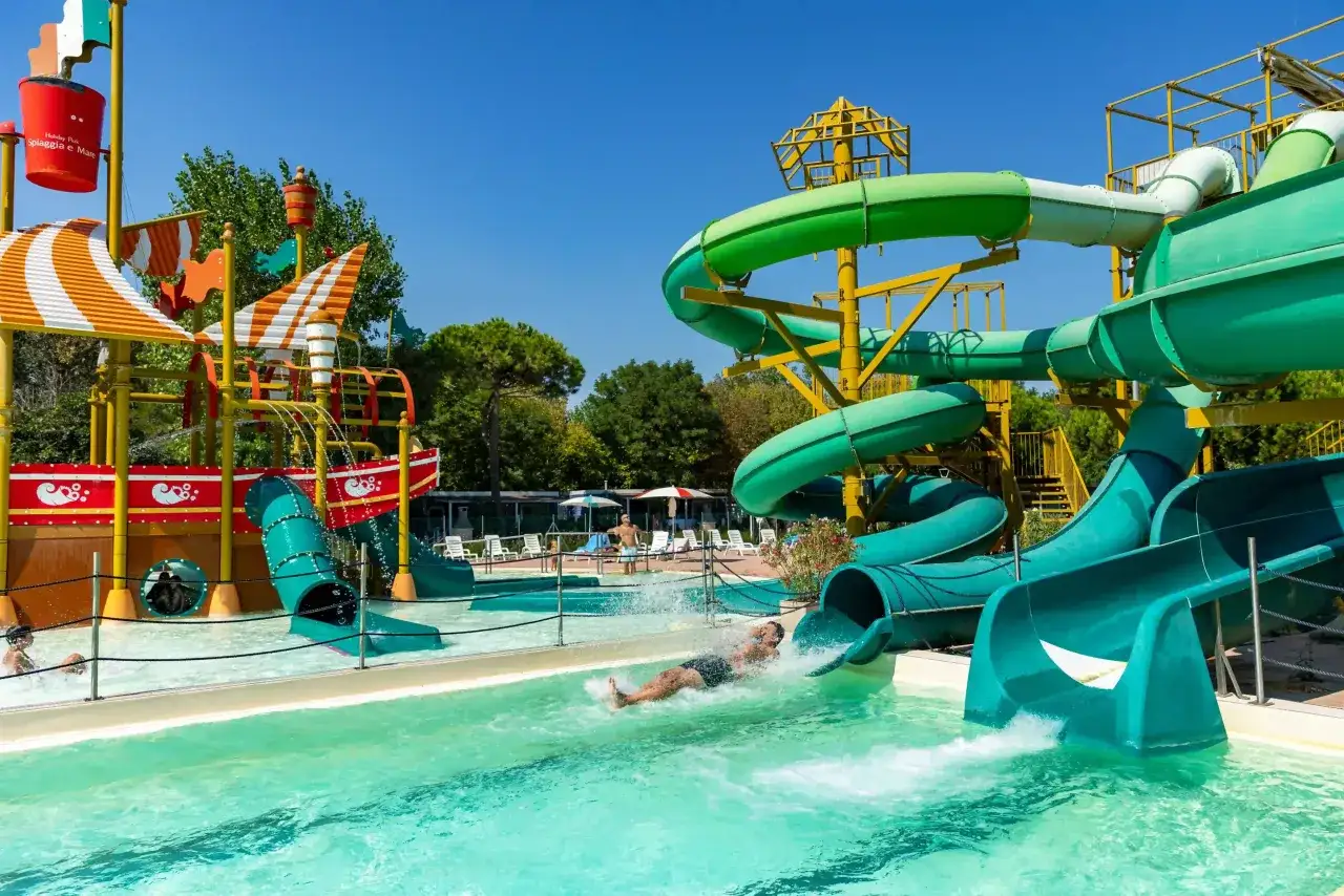 Scivoli acquatici colorati e divertenti, perfetti per i campeggi in Emilia Romagna per bambini. Un uomo scende a tutta velocità!