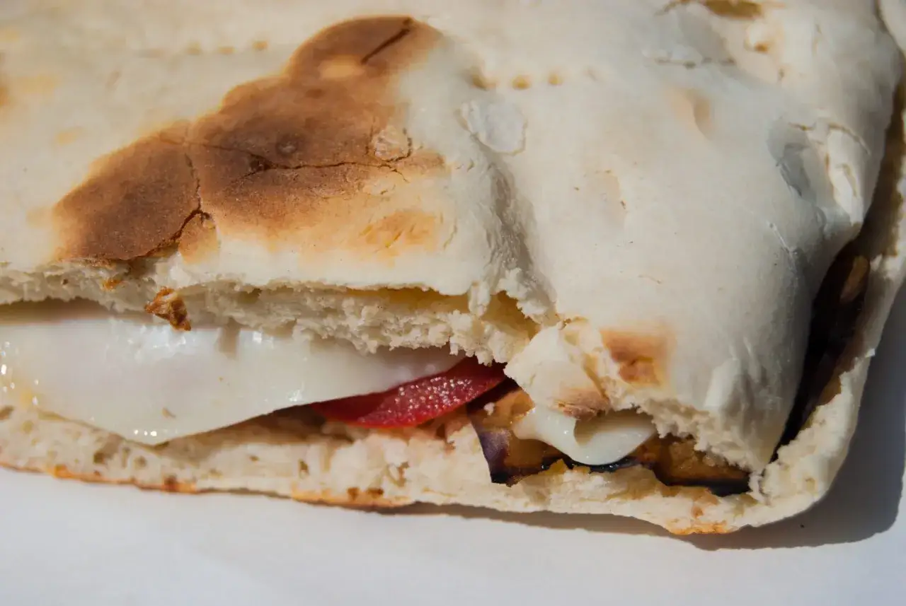 Un panino con mozzarella filante, pomodoro e melanzane grigliate, un assaggio di vero mangiare in Umbria.