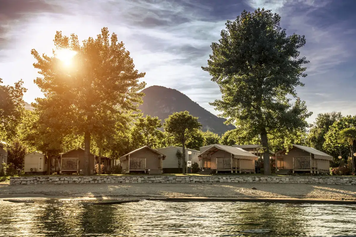 Accogliente agricampeggio in Piemonte con bungalow in legno e tende glamping, bagnati dalla luce dorata del sole al tramonto.