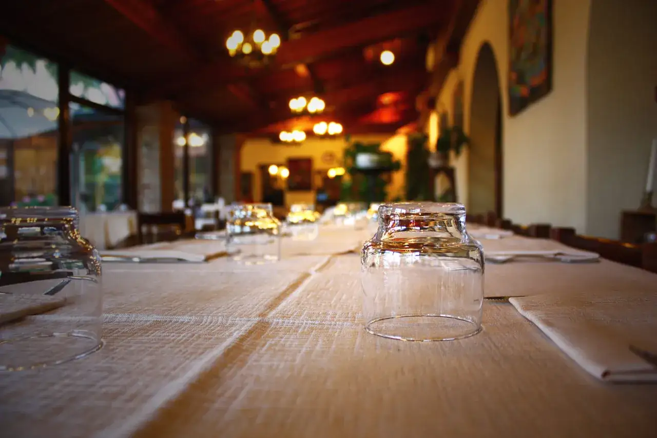 Tavola apparecchiata in un ristorante, bicchieri capovolti e tovaglioli pronti per accogliere i sapori della gastronomia Friuli Venezia Giulia.