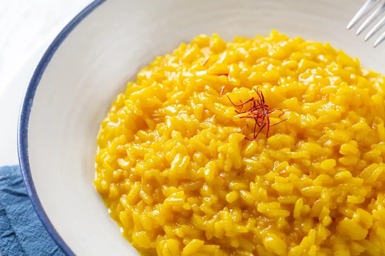 Risotto alla Milanese, un classico da provare per scoprire cosa mangiare in Lombardia. Cremoso, giallo zafferano e profumato.