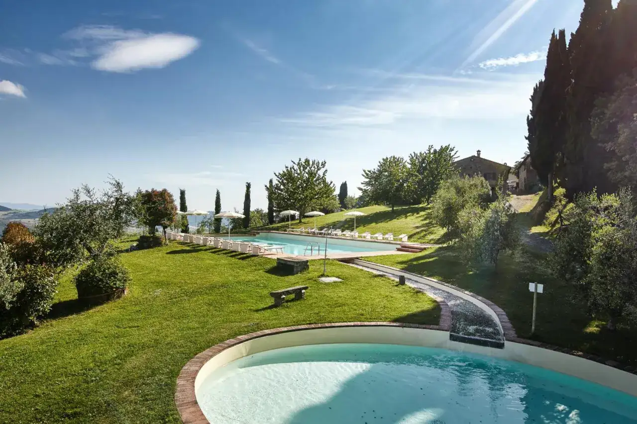 Piscine e prato verde in Toscana, ideale per un weekend con bambini all'insegna del relax e del divertimento sotto il sole.