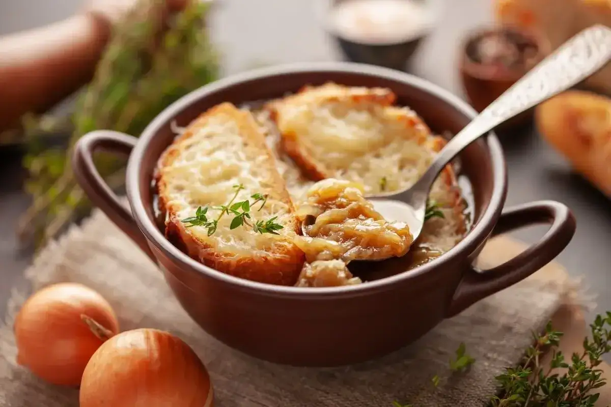 Zuppa di cipolle fumante, con crostini gratinati e un rametto di timo. La carabaccia, un classico confortante.
