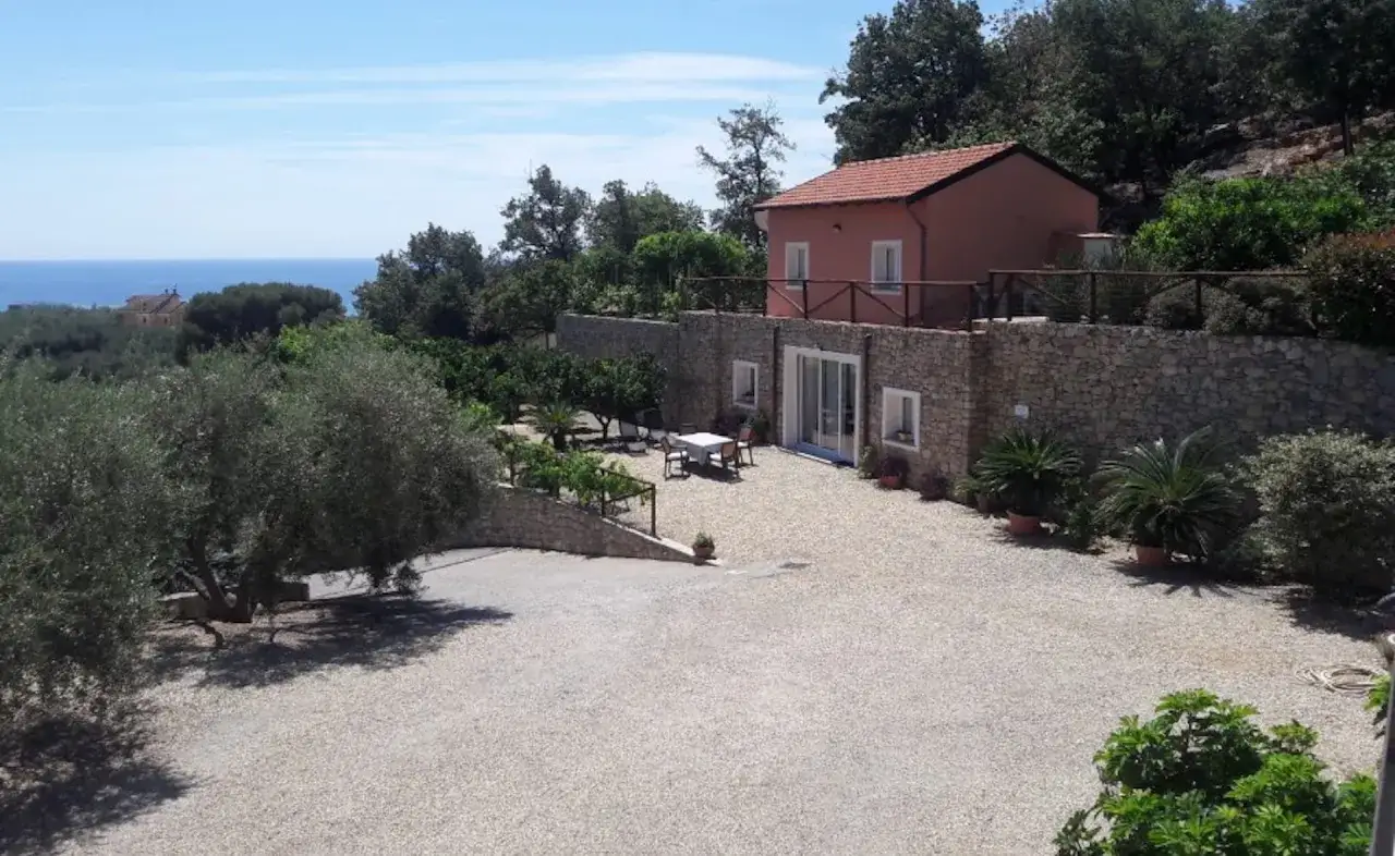 Agriturismi entroterra ligure: casa con tetto rosso, muretti in pietra, ulivi secolari e vista mare.