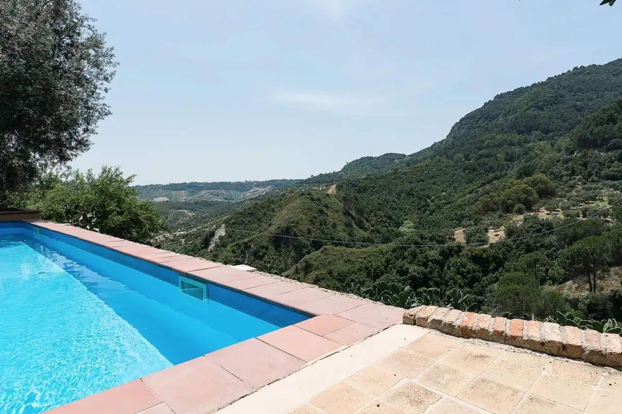 Piscina con vista panoramica su colline verdi, ideale per scoprire gli agriturismi in Calabria.