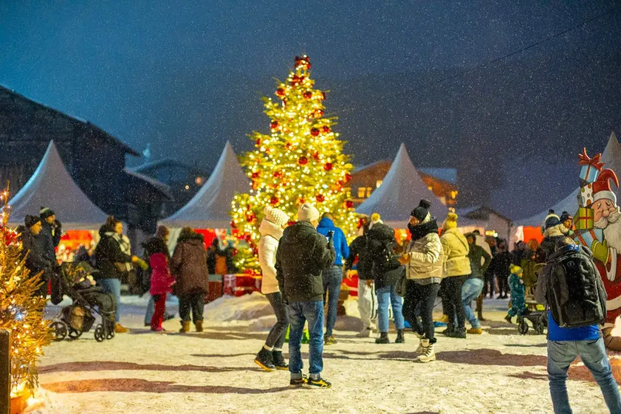 Un magico natale in montagna con bambini, tra bancarelle innevate e un albero scintillante.
