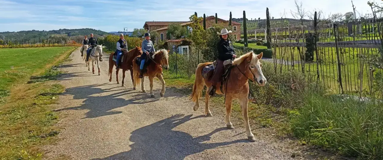 Cavalcata in un maneggio toscana, tra colline verdi e casali.