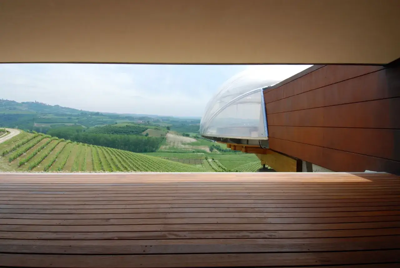 Terrazza in legno con vista su vigneti e colline, ideale per una degustazione vini Piemonte in un ambiente moderno.
