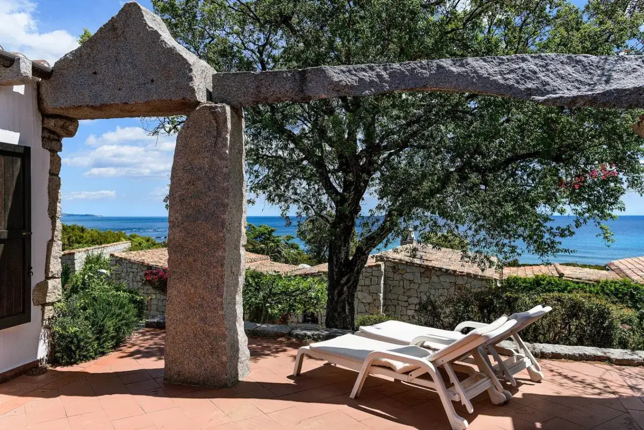 Terrazza con vista mare, lettini prendisole e un arco in pietra. Un assaggio dei migliori agriturismi Sardegna sud.