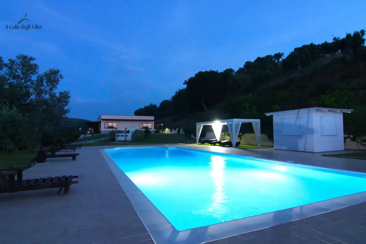 Agriturismo in Calabria con piscina illuminata, lettini e gazebo. Un'oasi di relax serale.