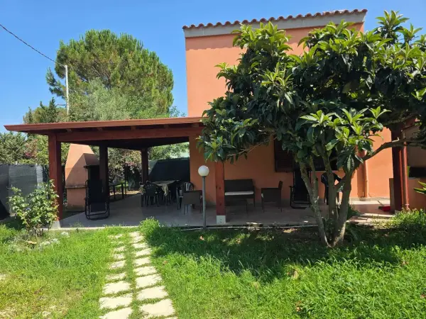Veranda con tavolo e sedie, barbecue e alberi da frutto. Un angolo di pace tra i migliori agriturismi Sardegna sud.